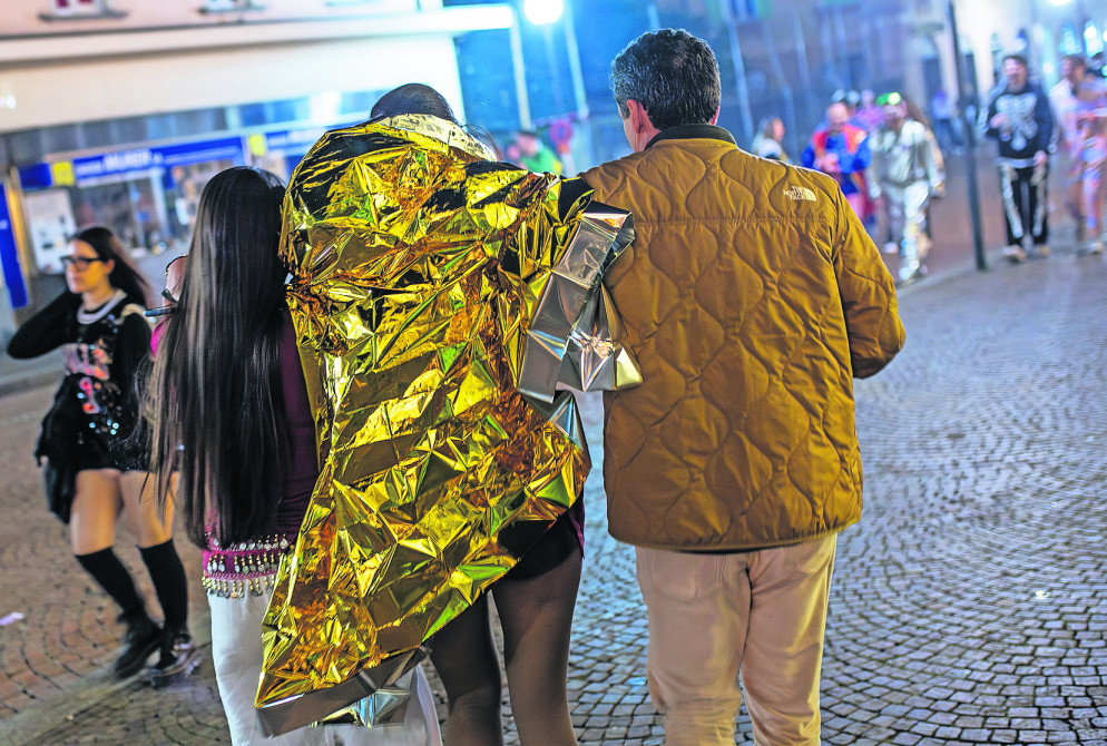 Un genitore si allontana con la figlia, avvolta nella mantellina termica, dopo averla prelevata dal punto di soccorso (foto Cdt - Gabriele Putzu)